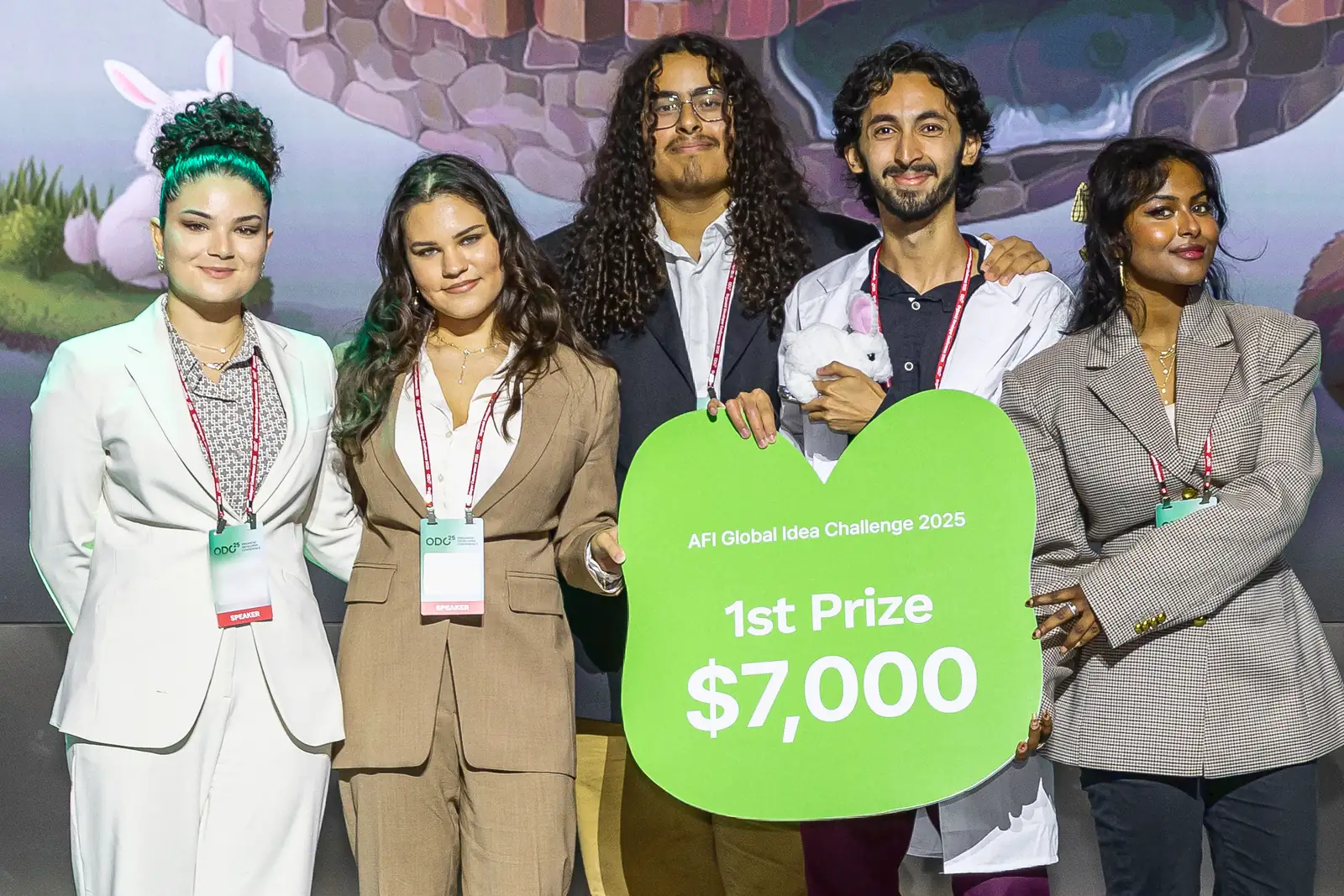 The five SkipLab teammates on stage in Seoul holding the green AFI Global Idea Challenge 2025 sign reading 1st Prize, $7,000; Mohammed, in a white lab coat, holds a small toy rabbit.